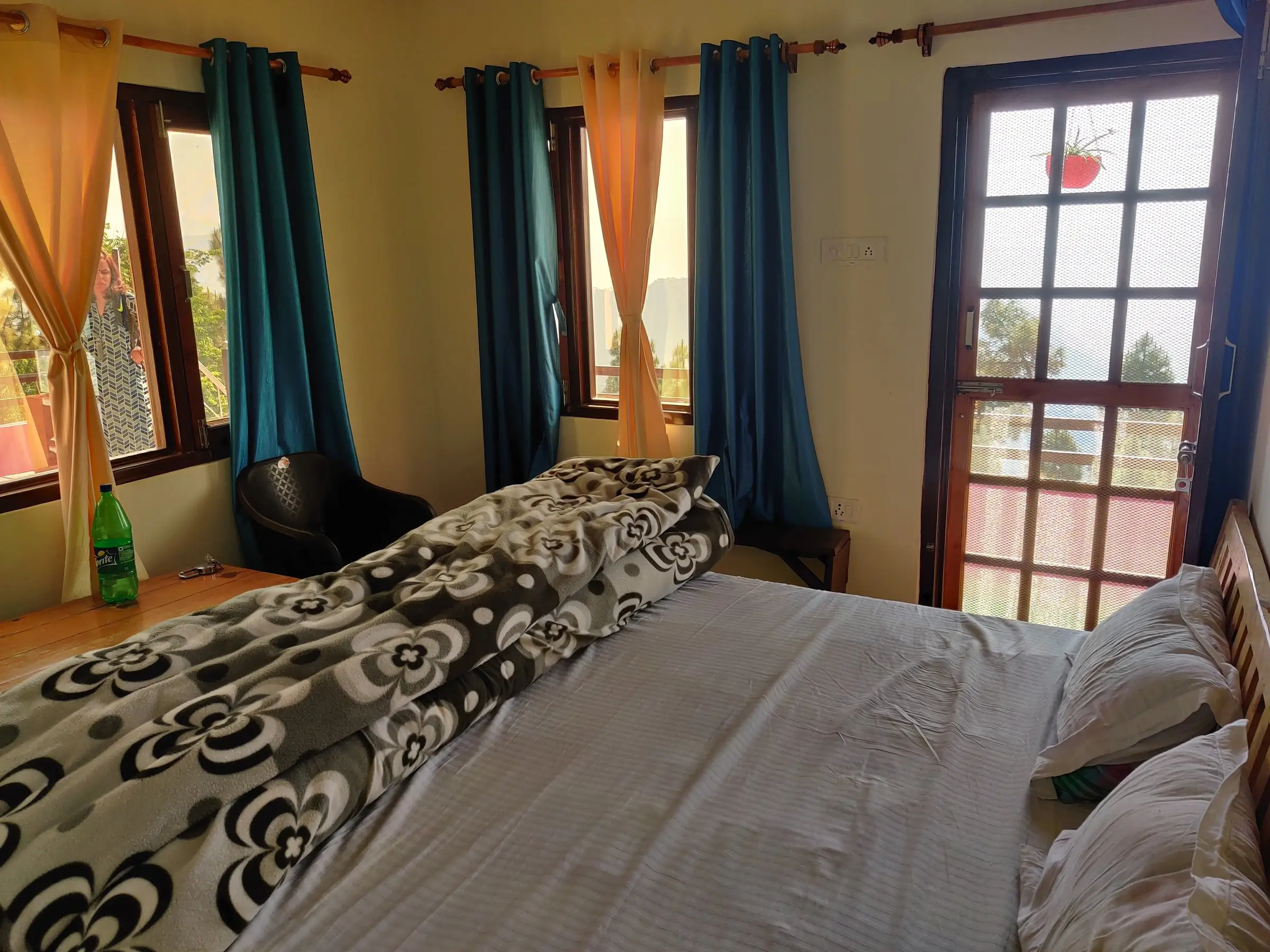 A double bed with blue curtains and a glazed door onto the balcony