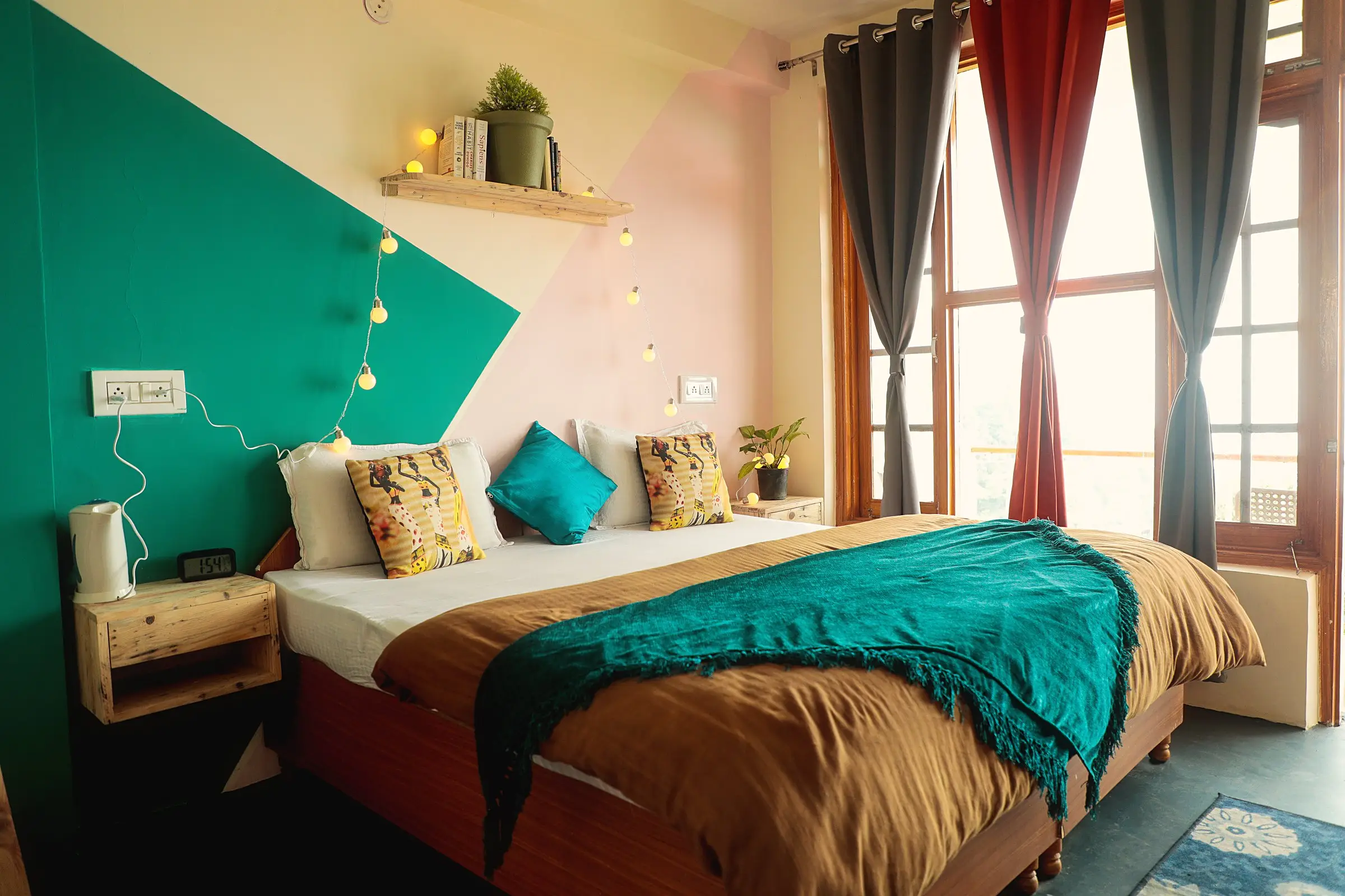 The bedroom, painted green and pink, with string lights over the double bed