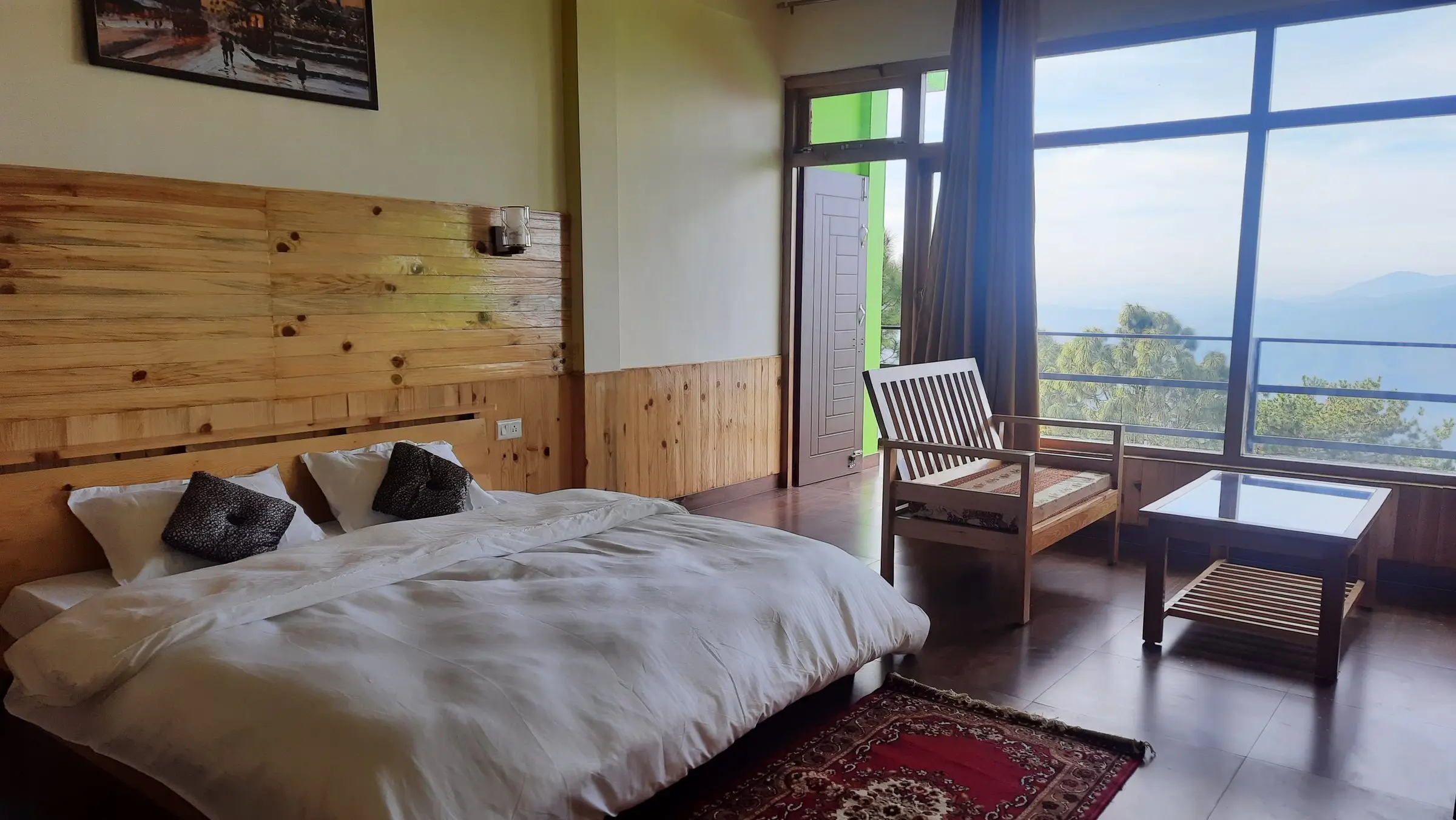 A double bed under a pine-panelled wall, with big windows onto the hills
