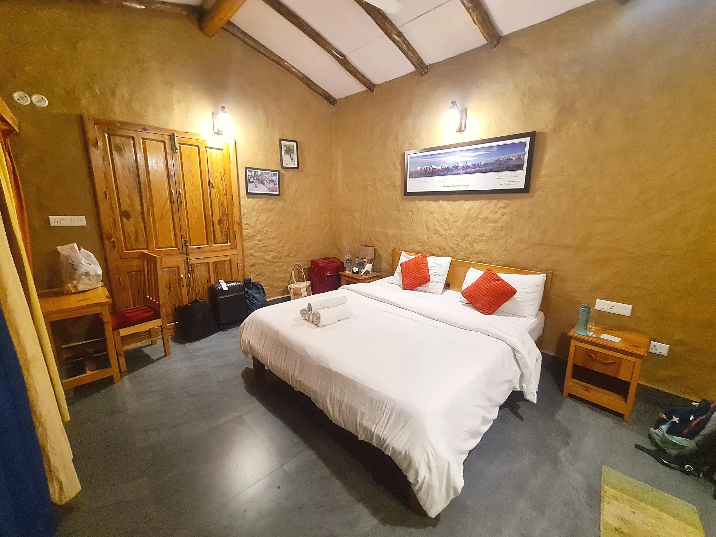 A double bed in a room with ochre plastered walls and roof beams