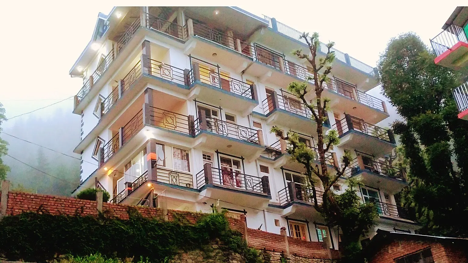 The building from below, tall and white with balconies on every floor