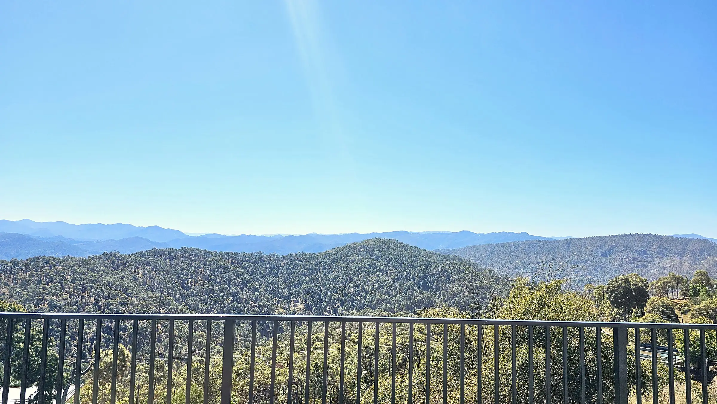 Forested ridges fading to blue, seen over a balcony railing