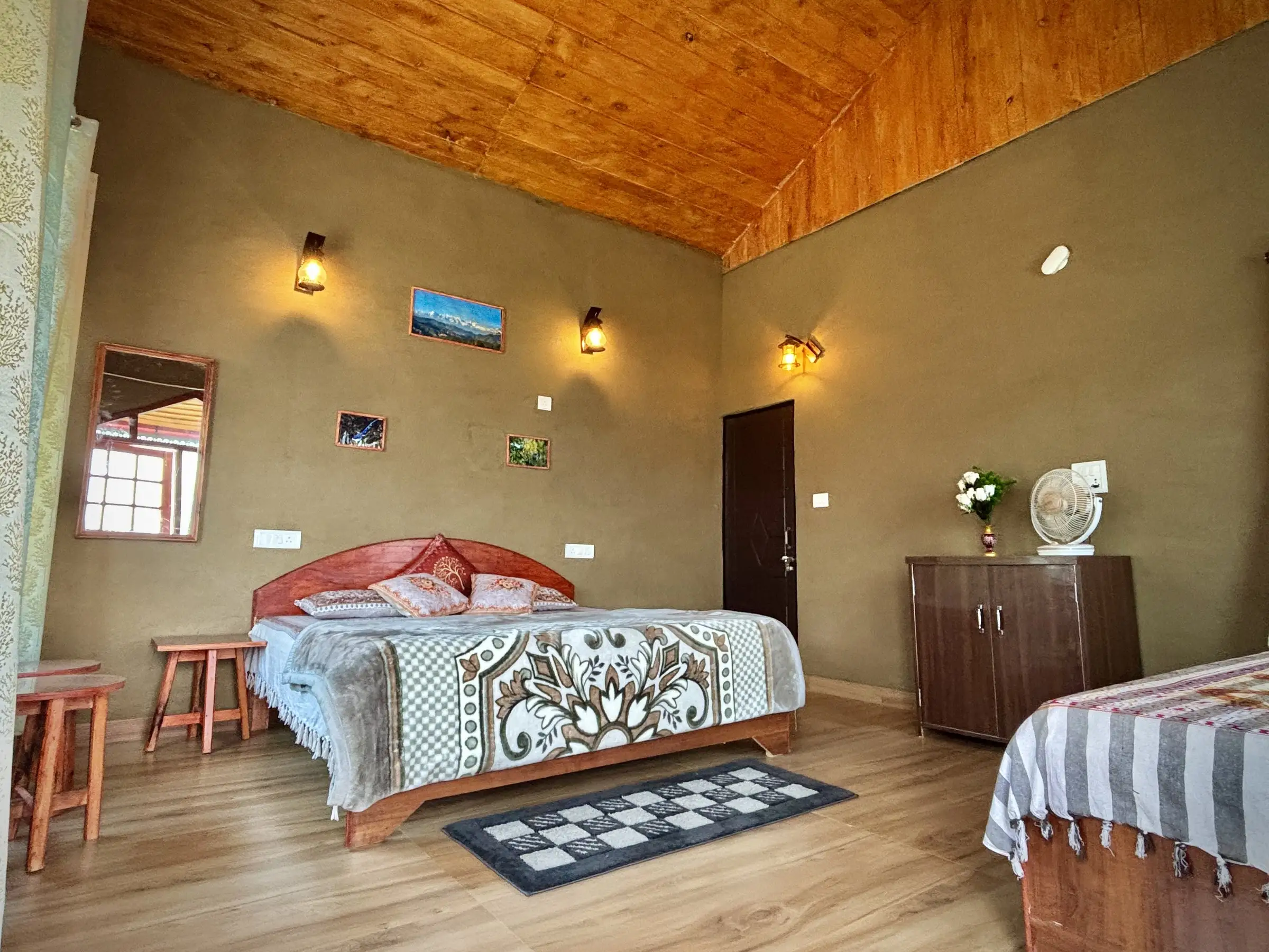 A room with olive walls, a wooden ceiling, two beds and a cabinet