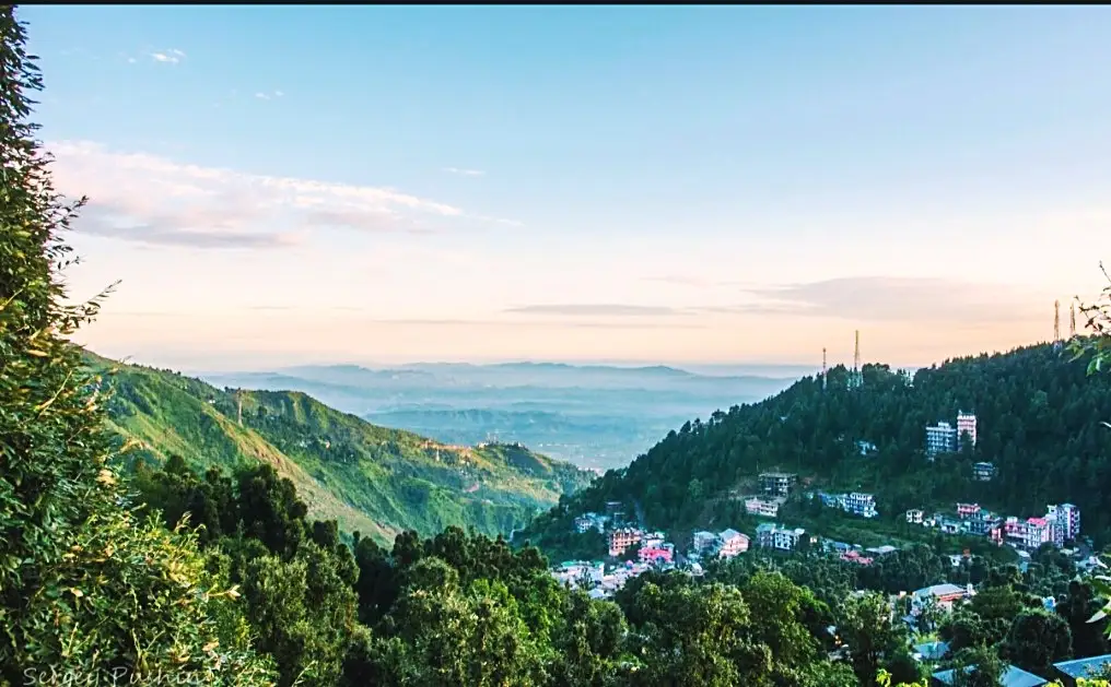 A wide view over forested slopes to the town and valley below