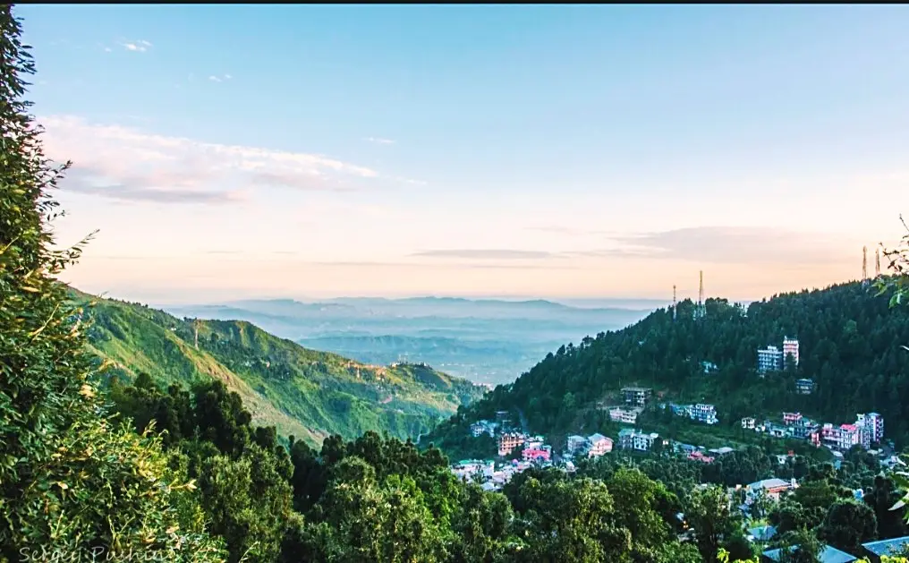A wide view over forested slopes to the town and valley below