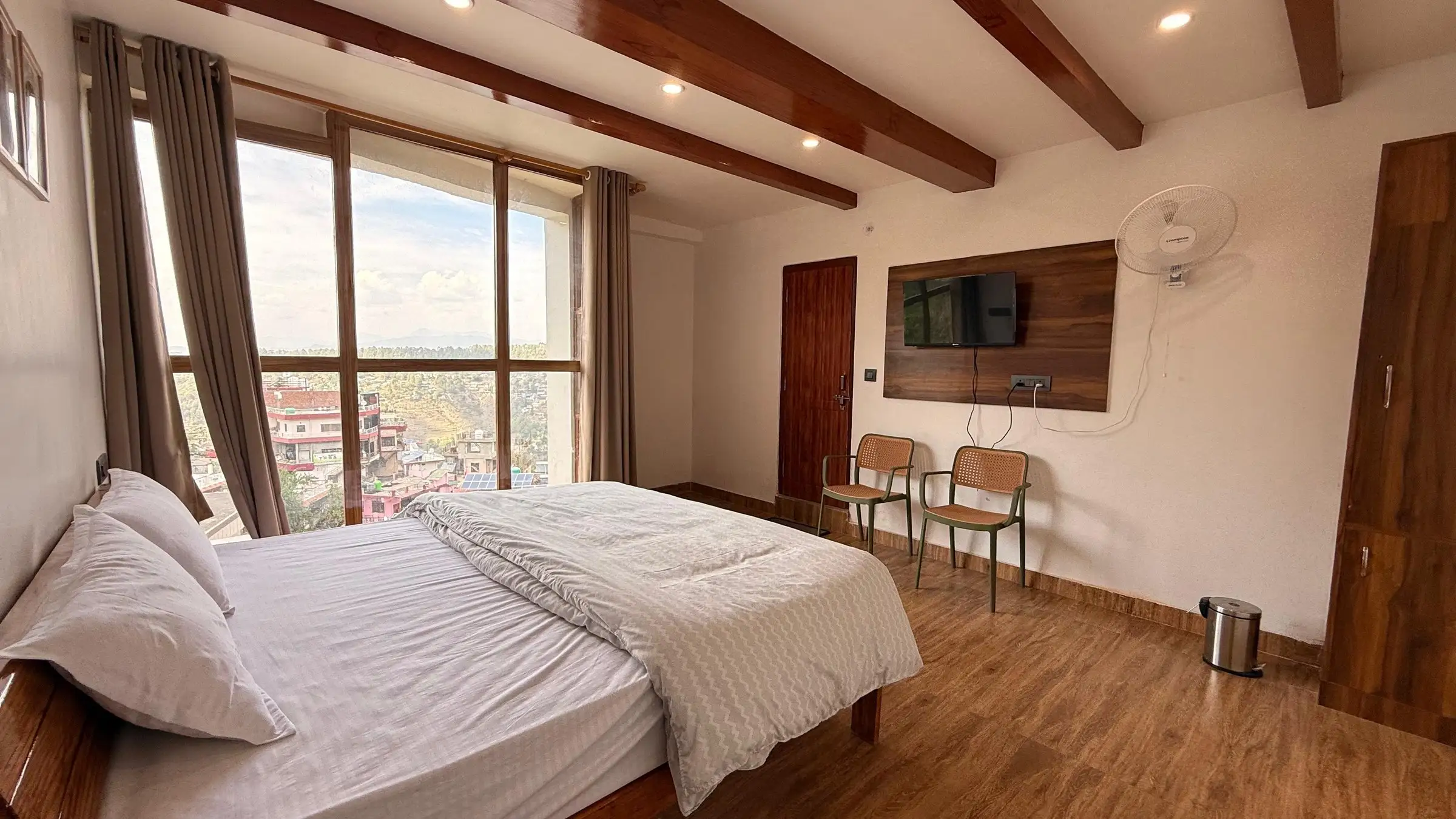 The bed beside the window wall, with a TV and two chairs opposite