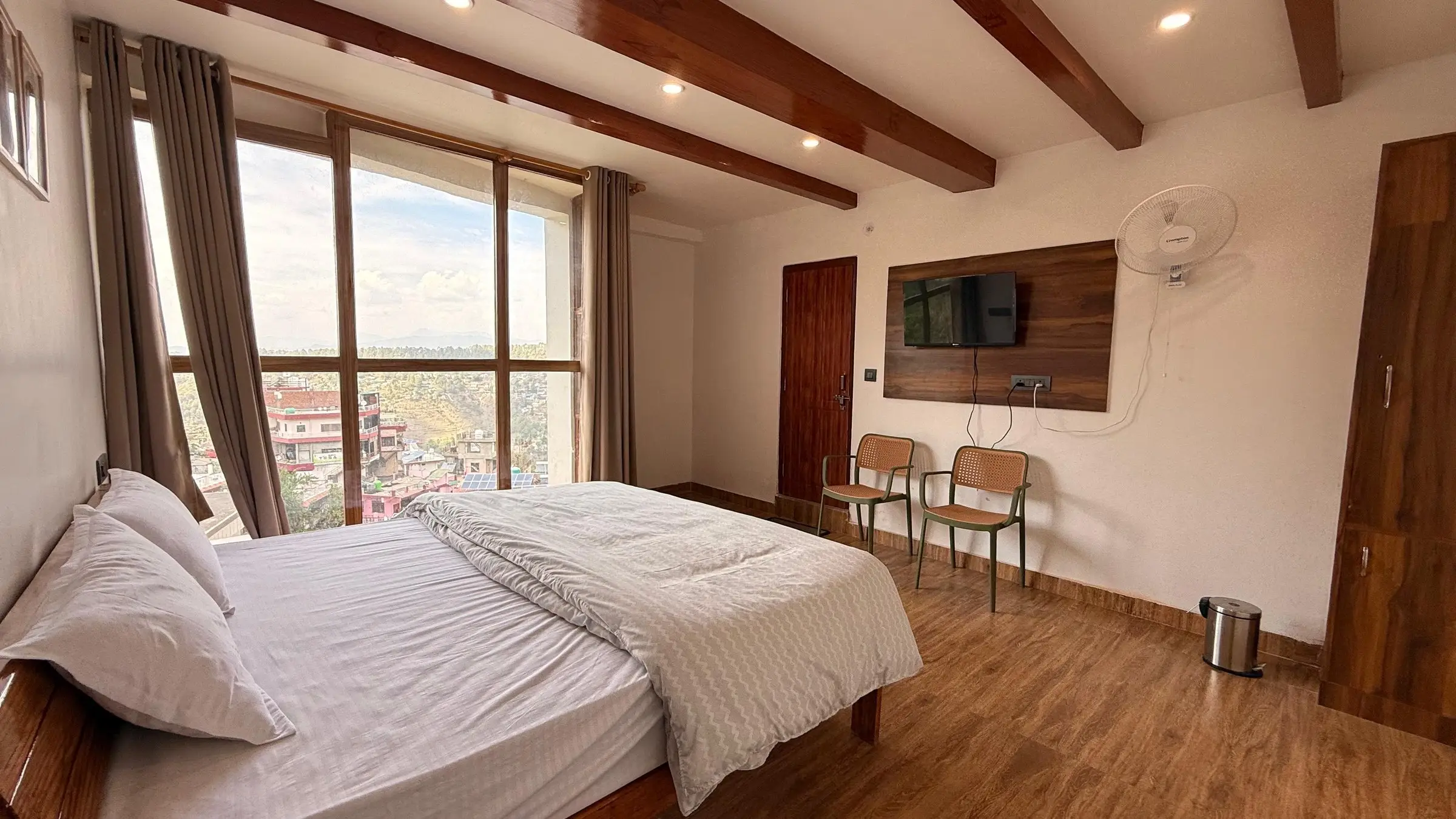 The bed beside the window wall, with a TV and two chairs opposite