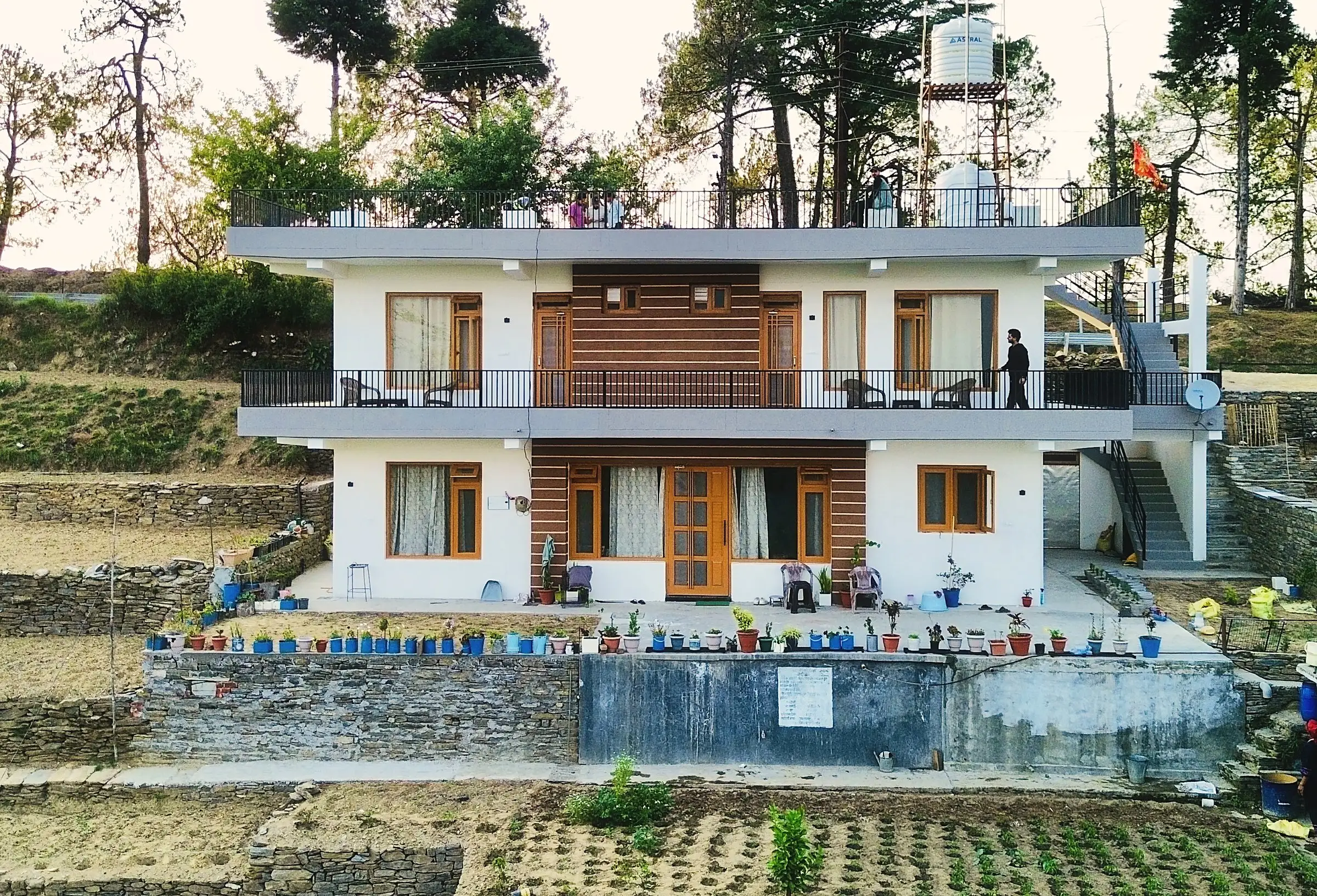 The two-storey white house with balconies, above terraced stone-walled fields