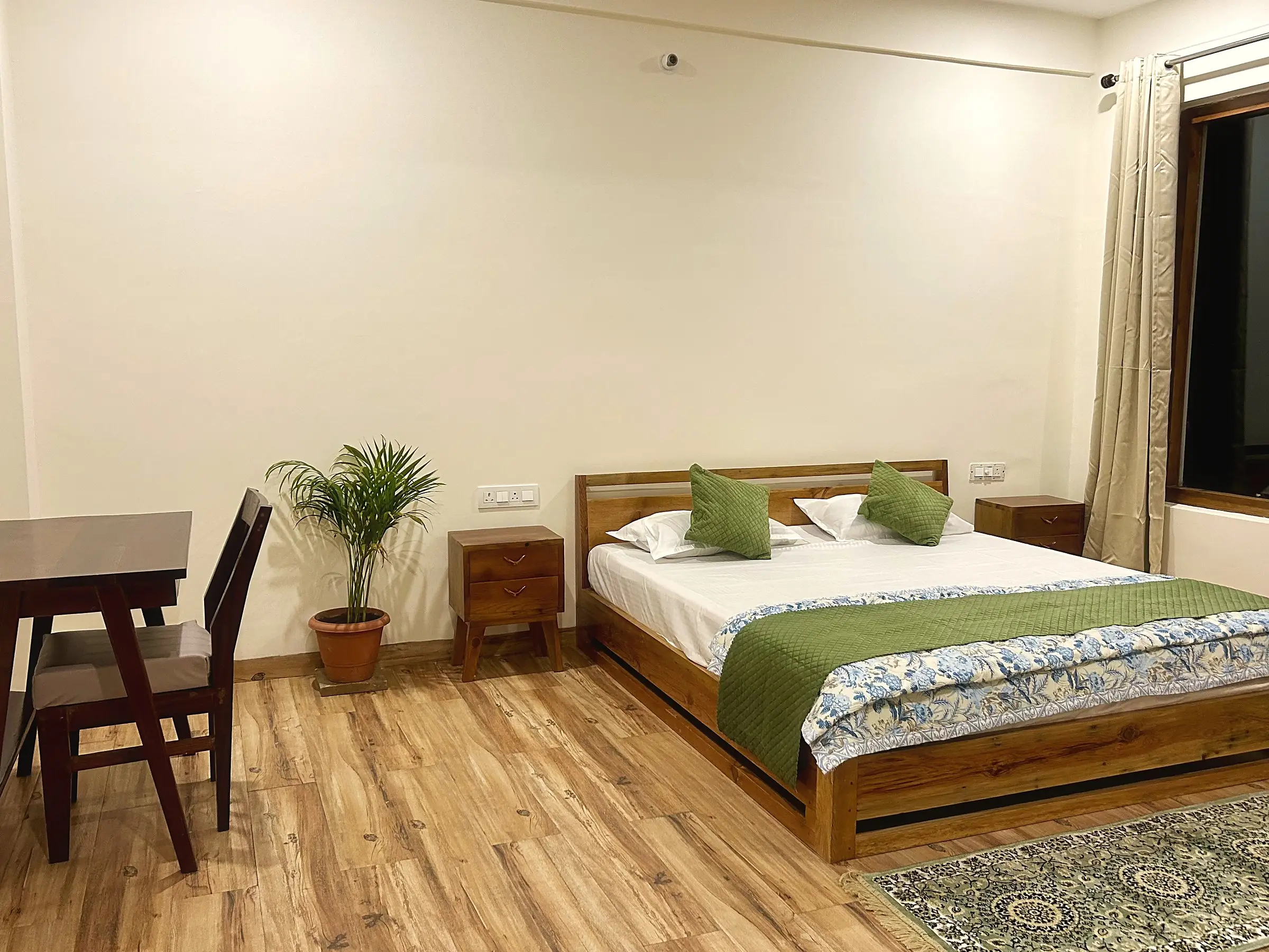 The bed, bedside tables, and a wooden desk and chair on the left