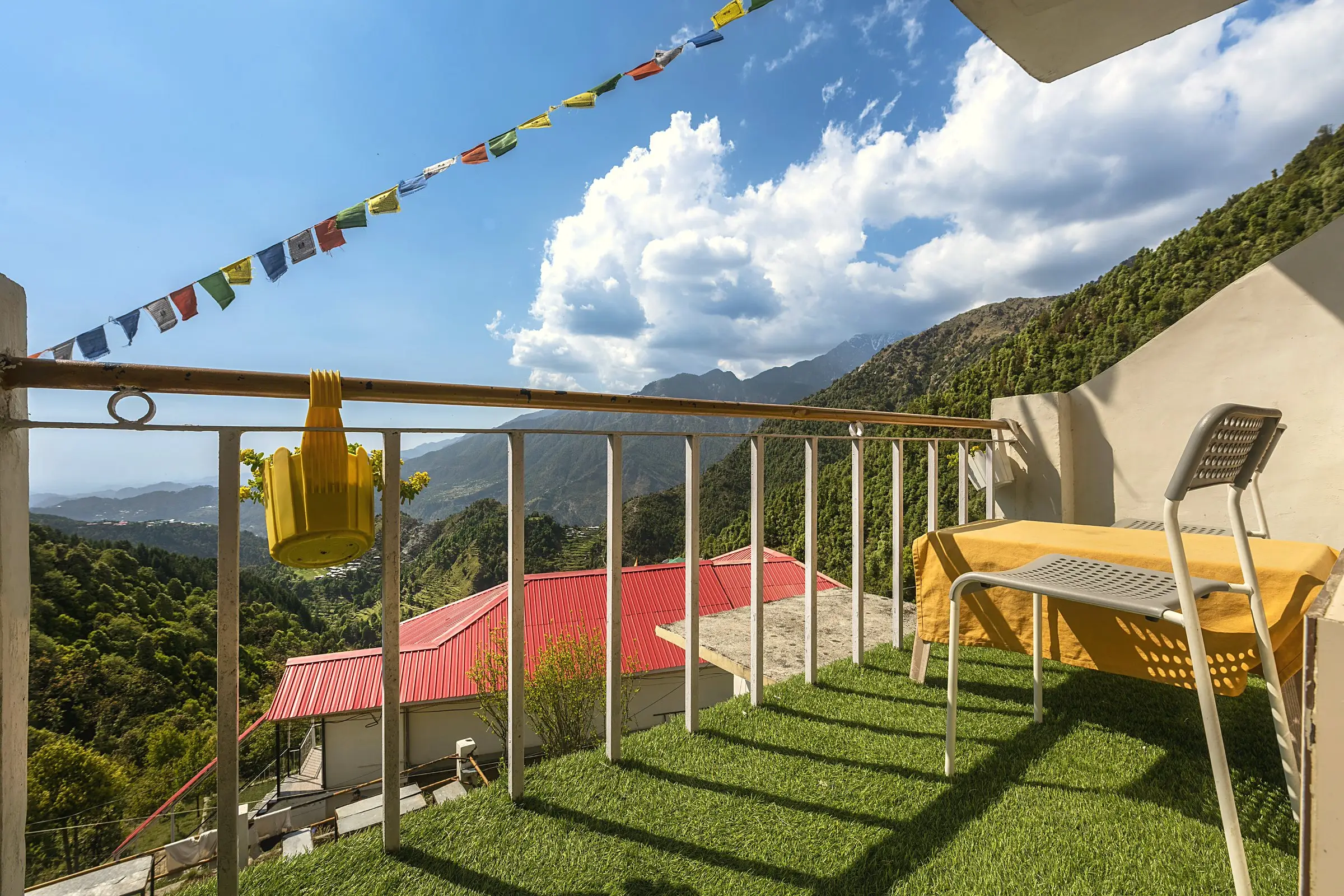 The balcony, with artificial grass, a table, a chair and prayer flags