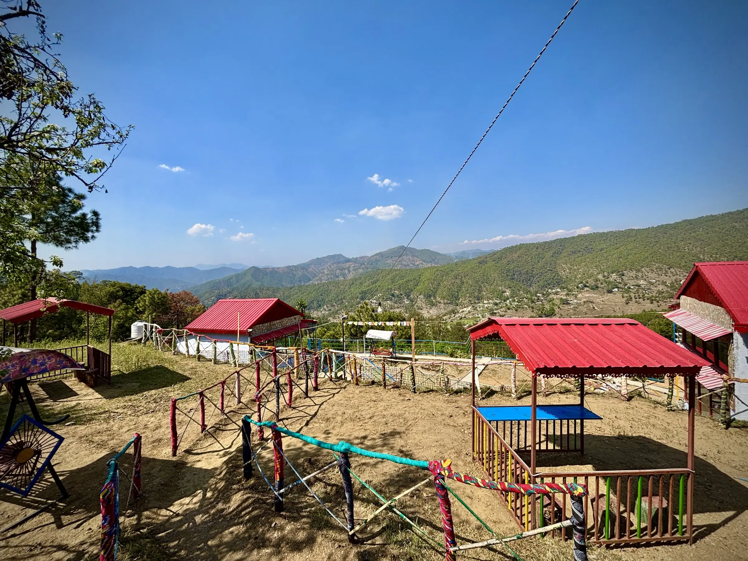 A yard with red-roofed pavilions and rope fencing, hills beyond