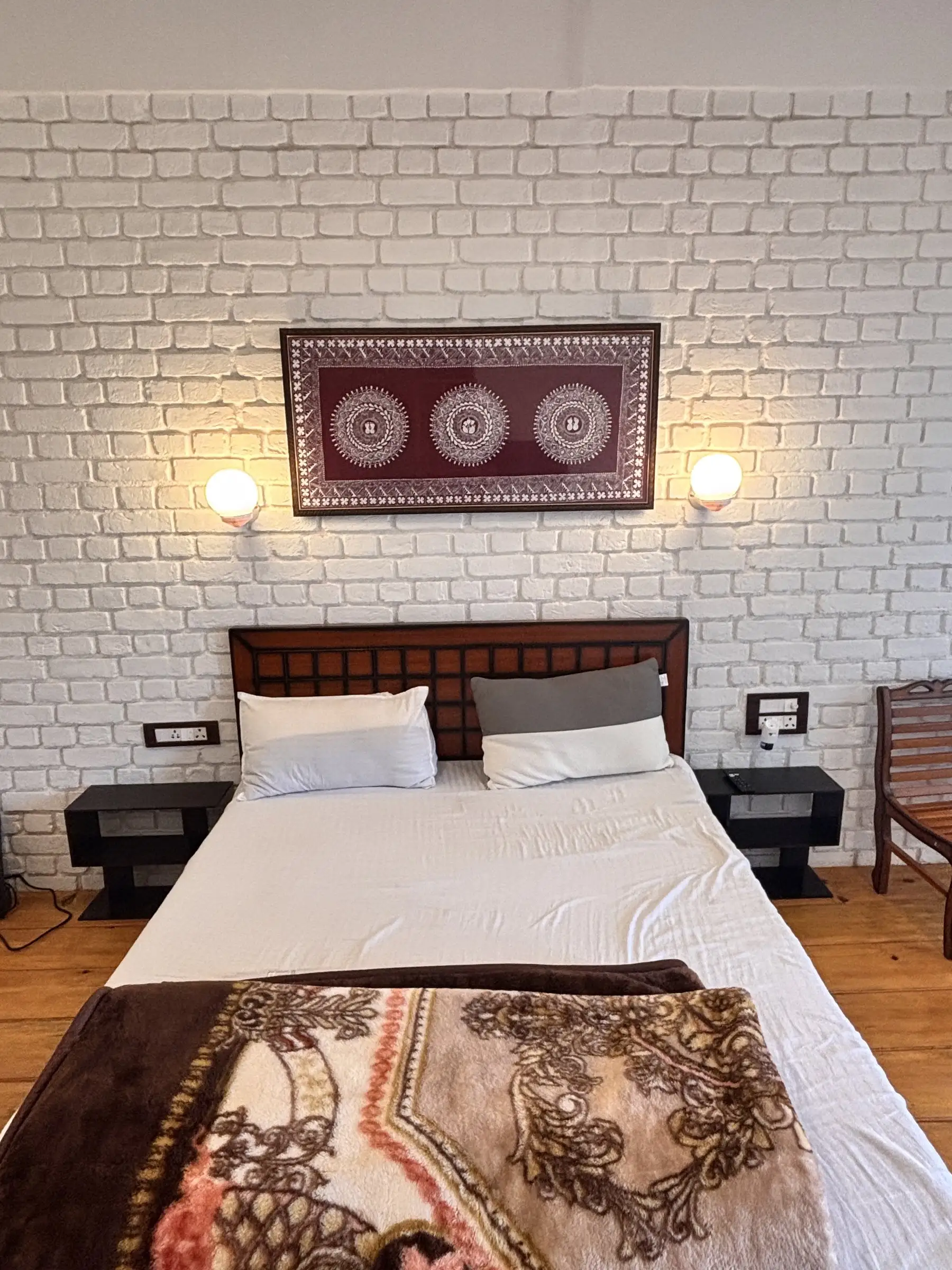 A double bed with a carved headboard against a white brick wall