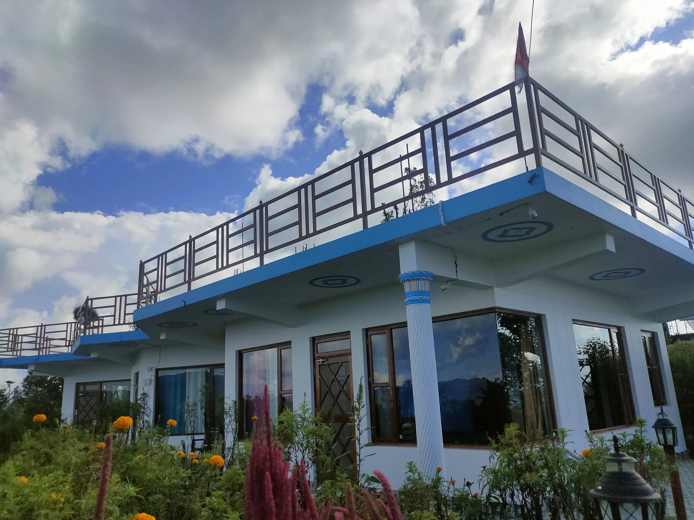 The white building with blue trim, a flat roof and orange flowers