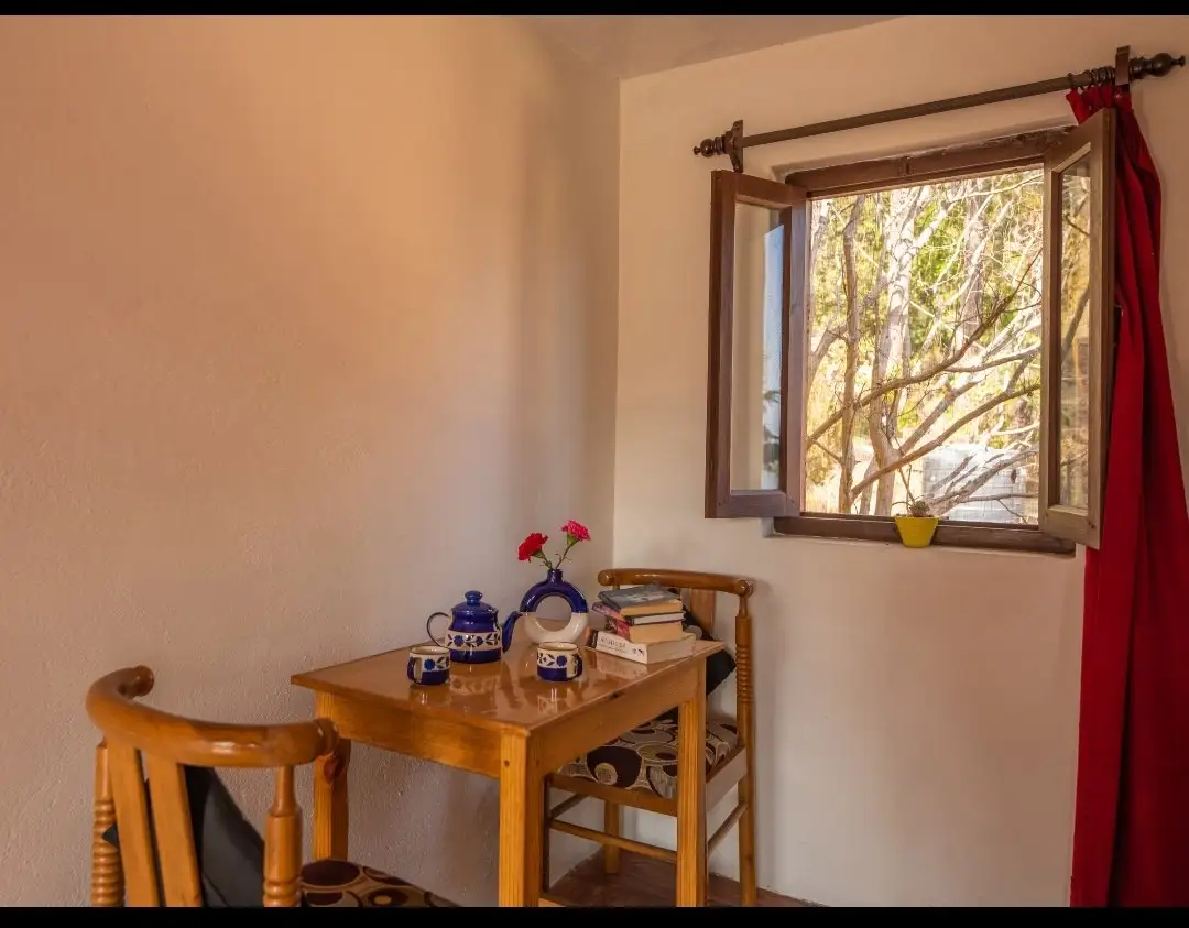 A small wooden table and two chairs beside an open window