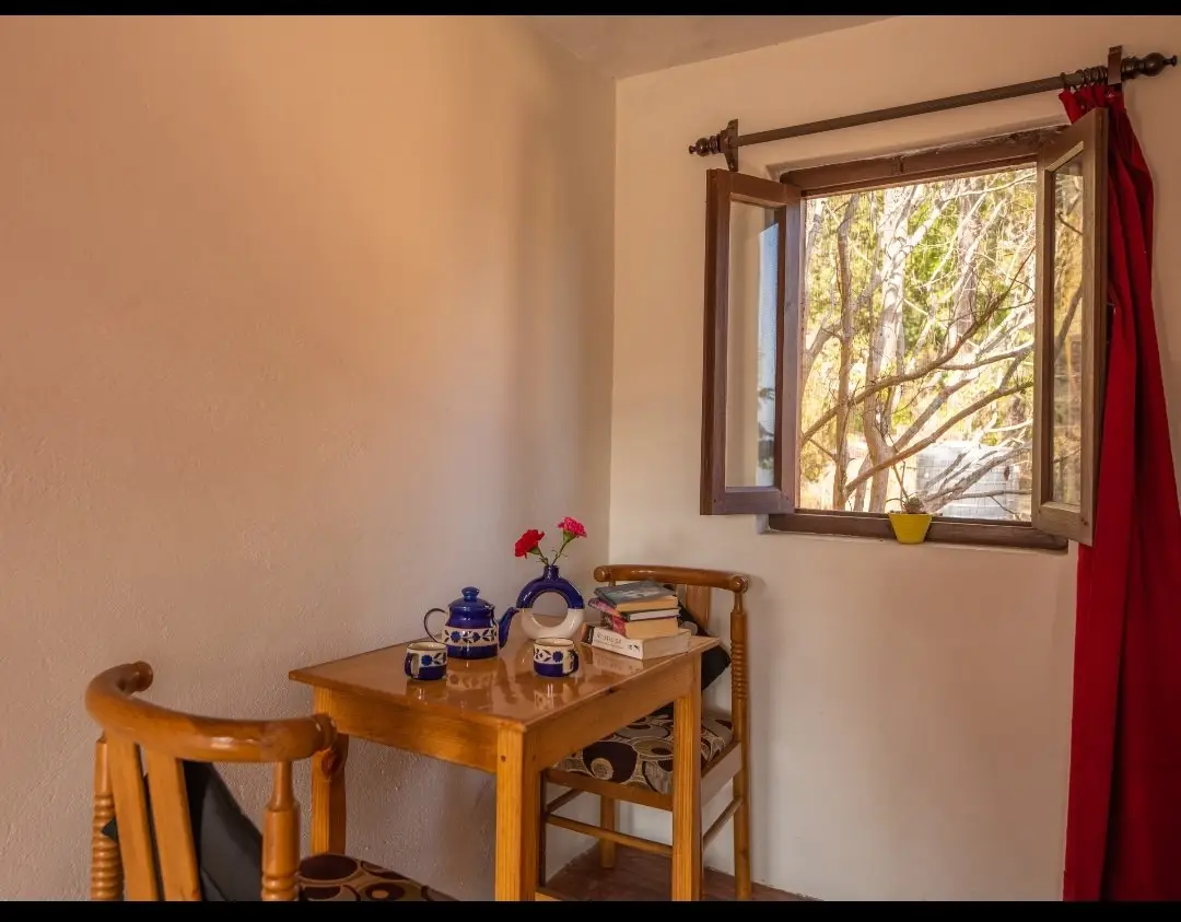 A small wooden table and two chairs beside an open window