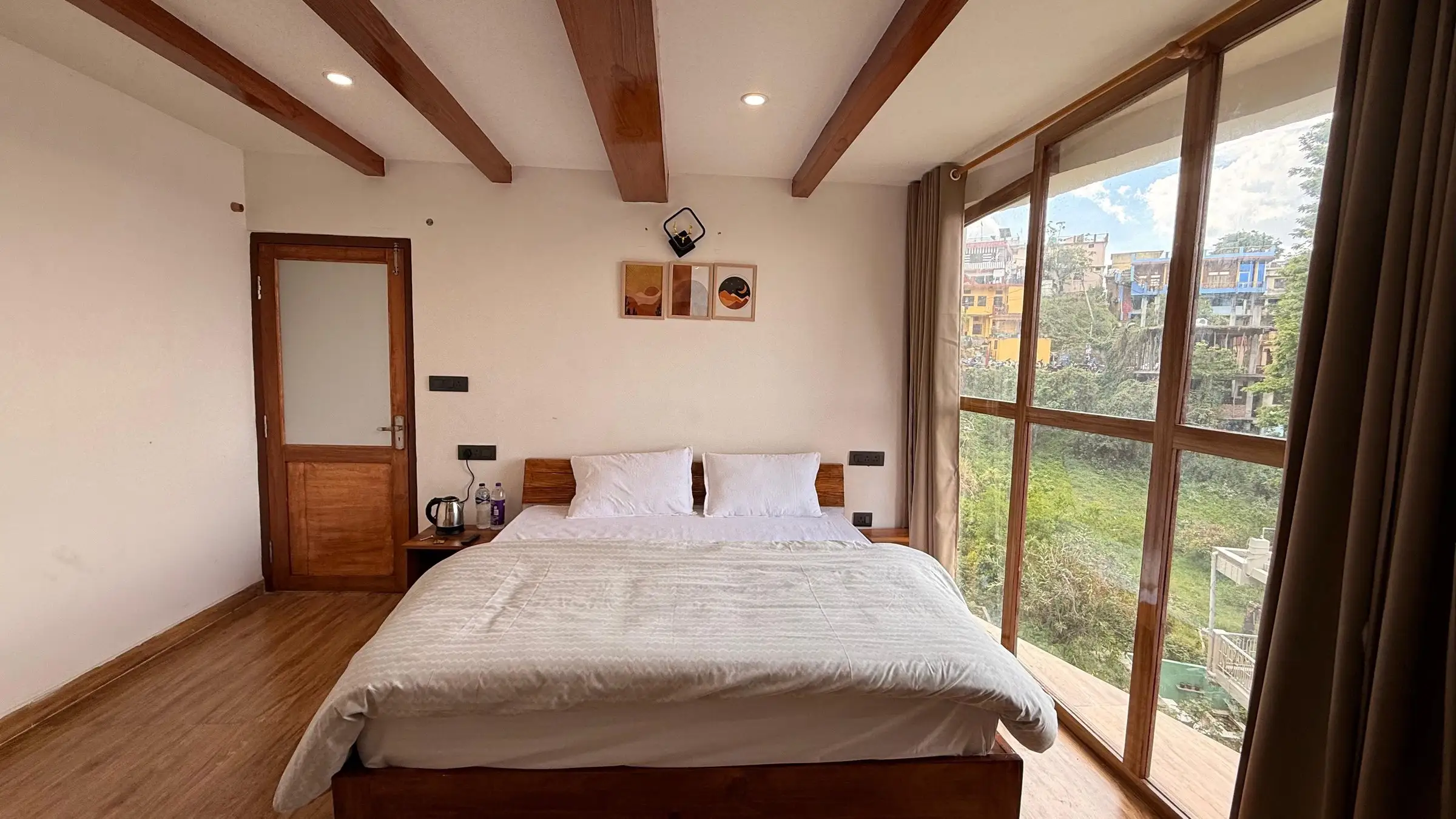 A bed with a wooden headboard, and a window onto a green slope