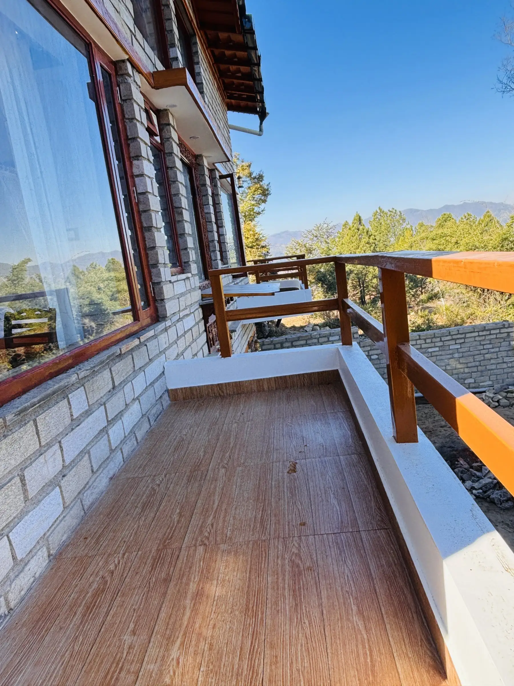 A narrow balcony with a wooden floor and an orange railing