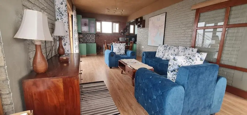 A sitting room with blue sofas, a coffee table and a wooden sideboard