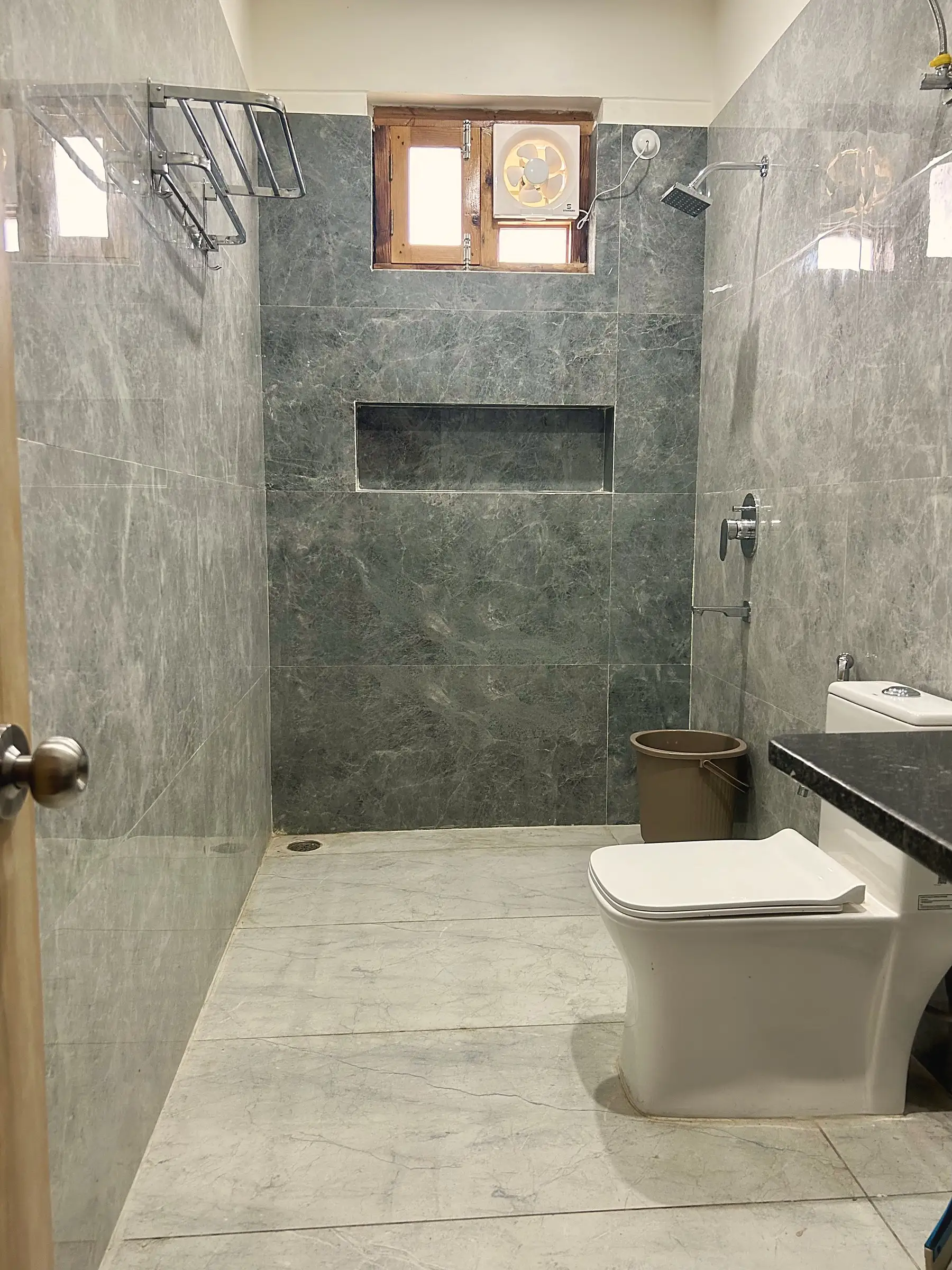 A grey-tiled bathroom with a walk-in shower and a toilet