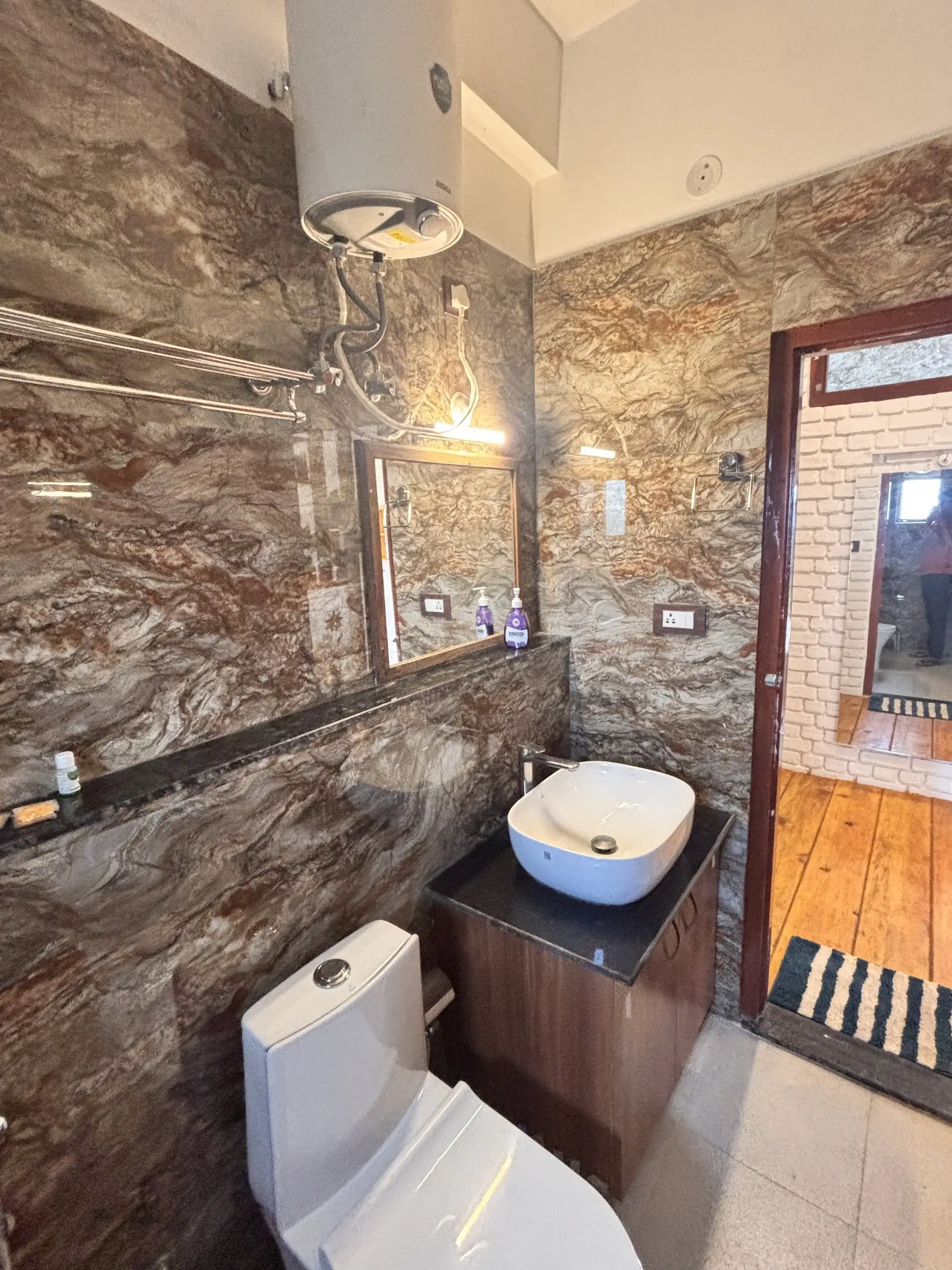 A bathroom with marble-look walls, a basin and a wall-mounted water heater