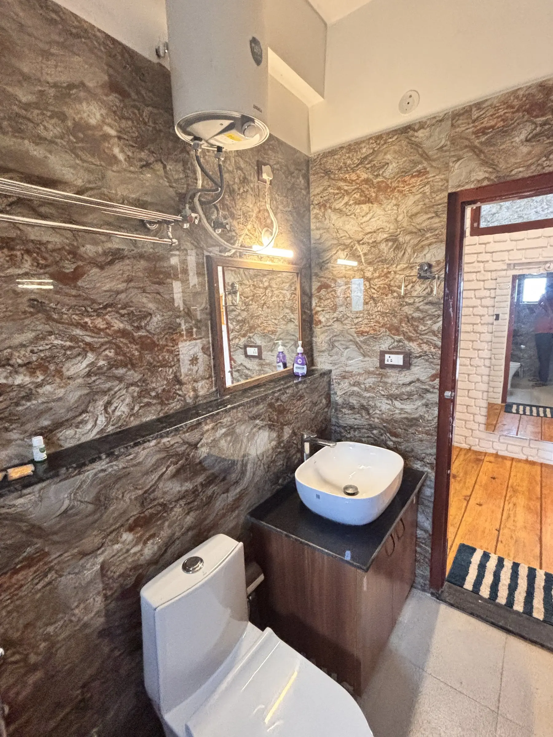 A bathroom with marble-look walls, a basin and a wall-mounted water heater