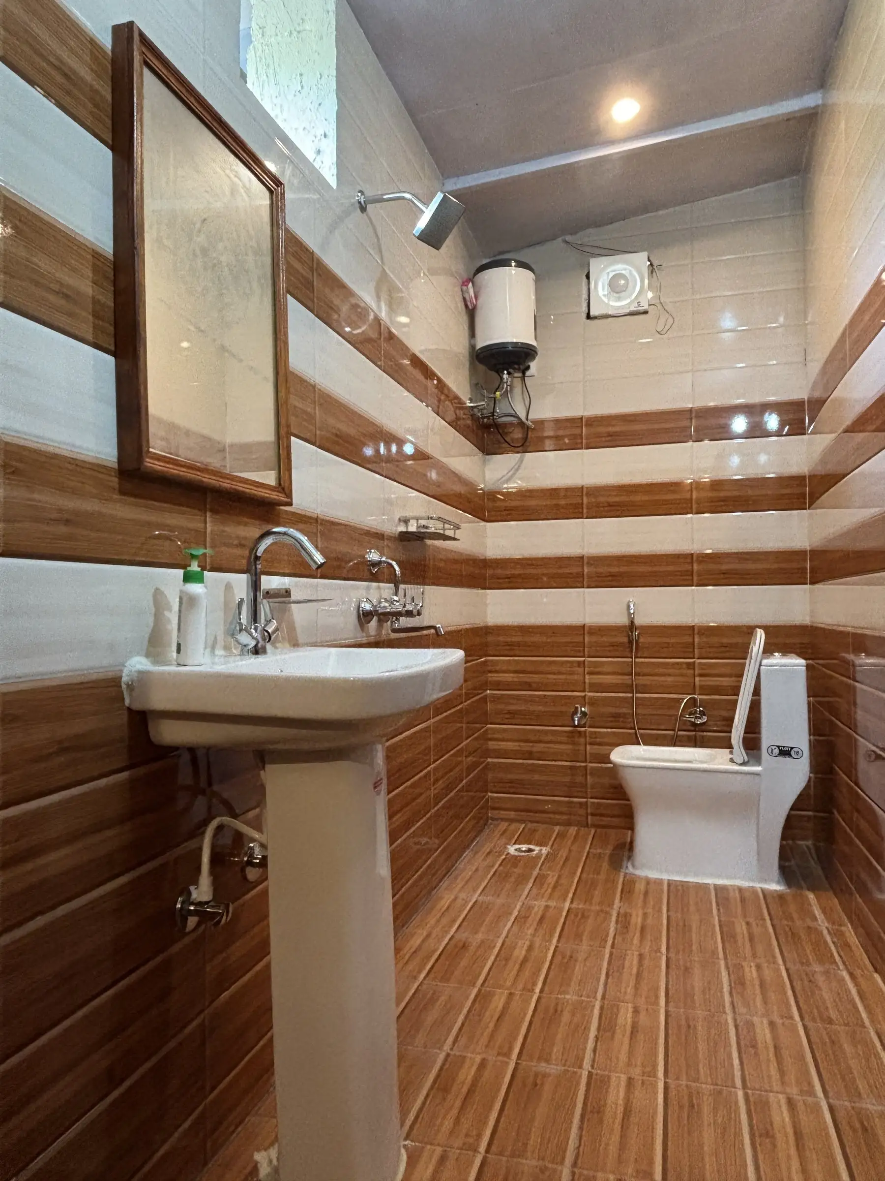 A bathroom with striped tiles, a basin, a shower head and a water heater