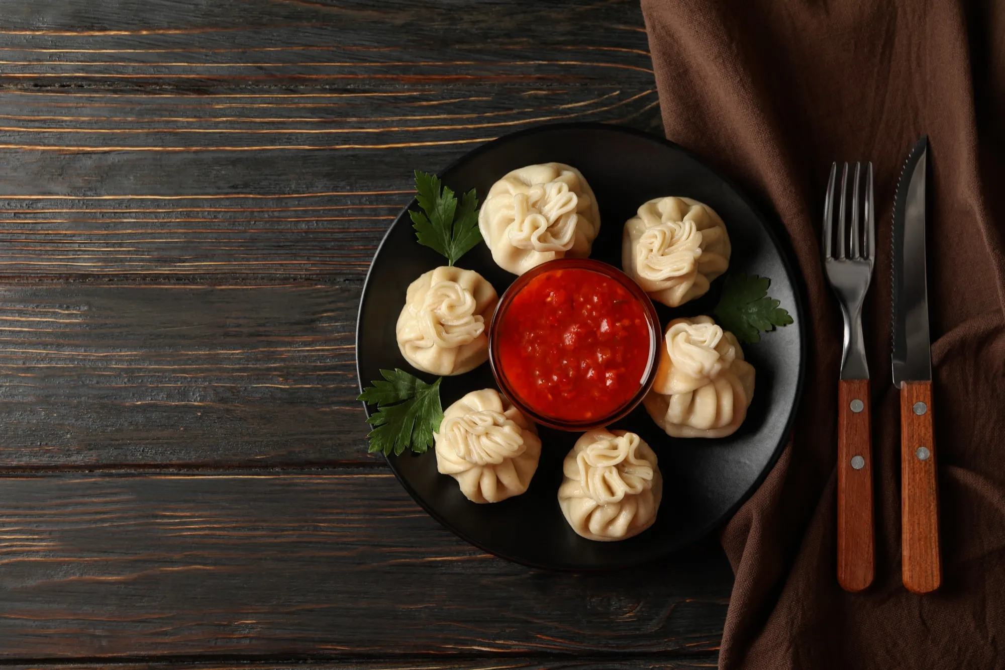 A plate of momos with red sauce