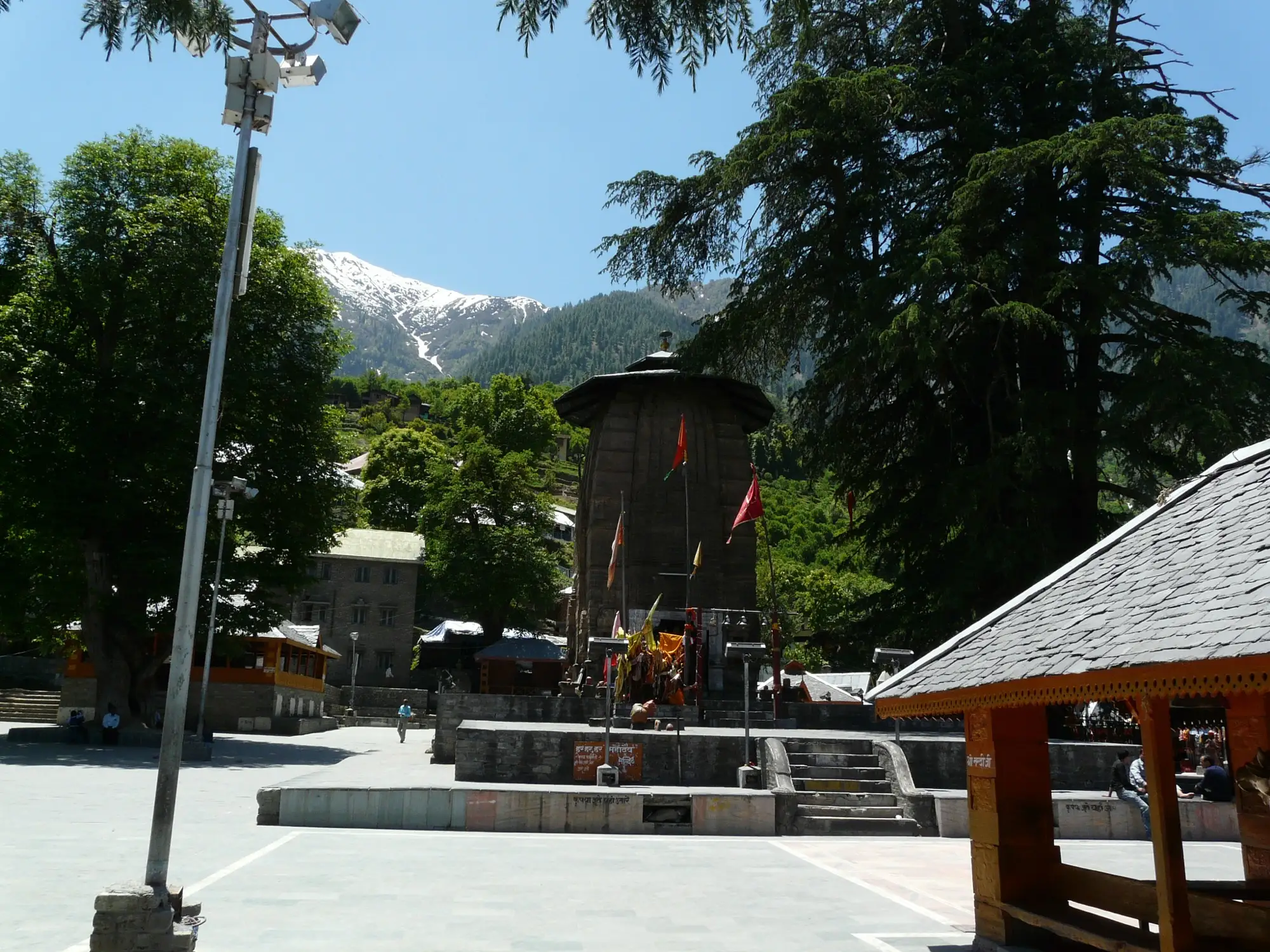 The stone shikhara of a Chaurasi temple, with a snow peak above the trees