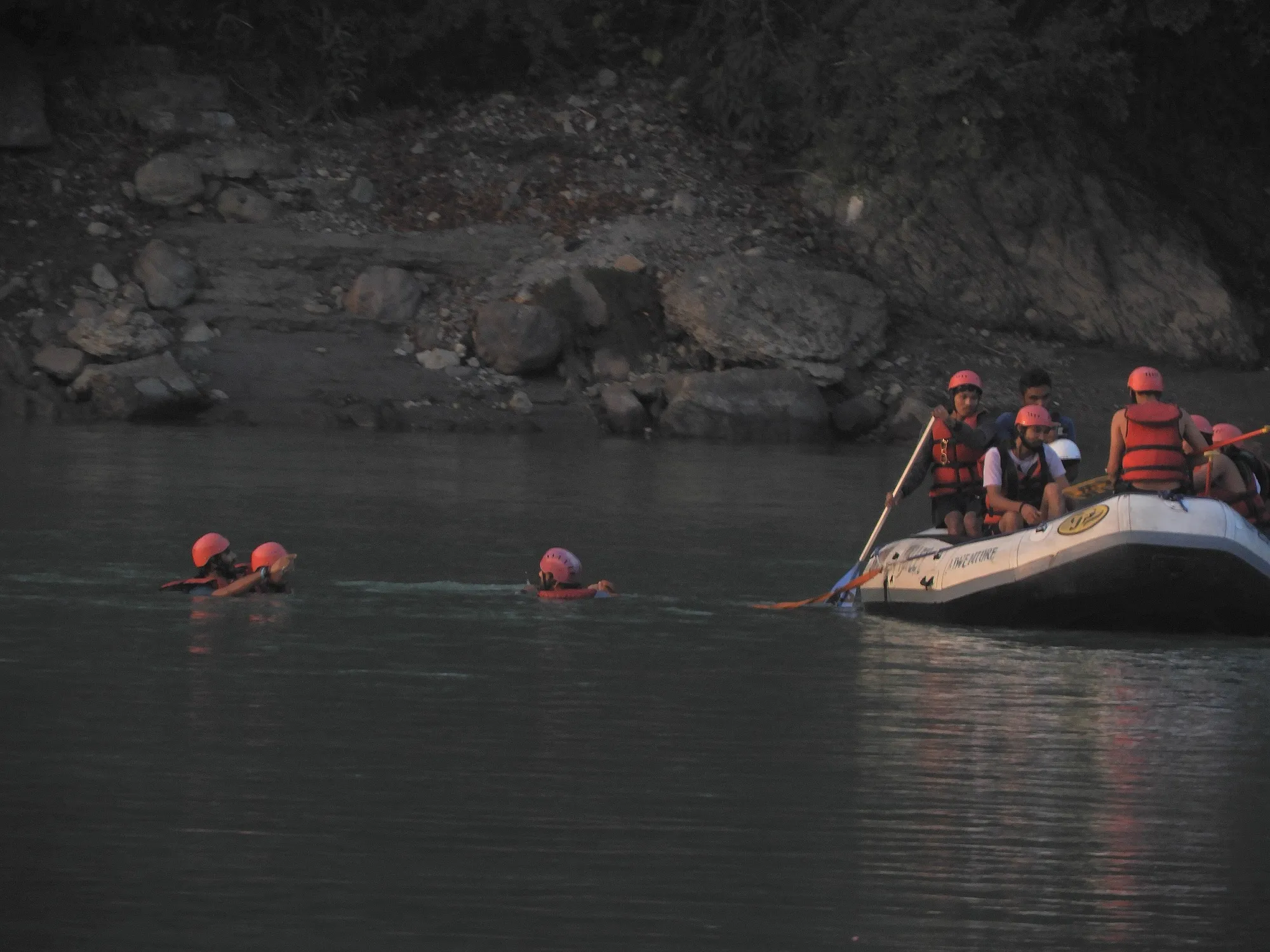 A raft with paddlers on the Ganga near Ram Jhula at dusk