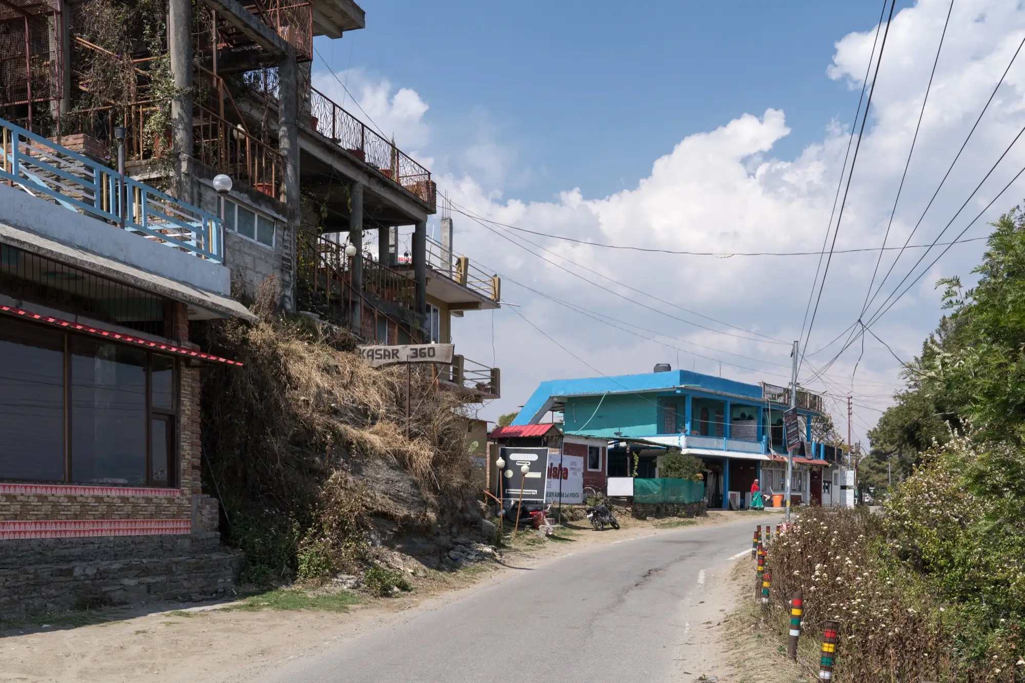 A narrow road lined with guest houses and shops in Kasar Devi, Almora