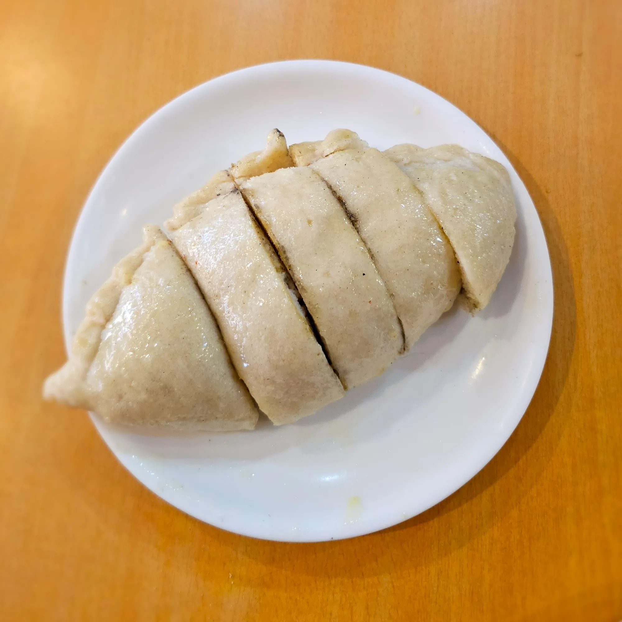 A sliced siddu, a steamed stuffed wheat bun, on a white plate