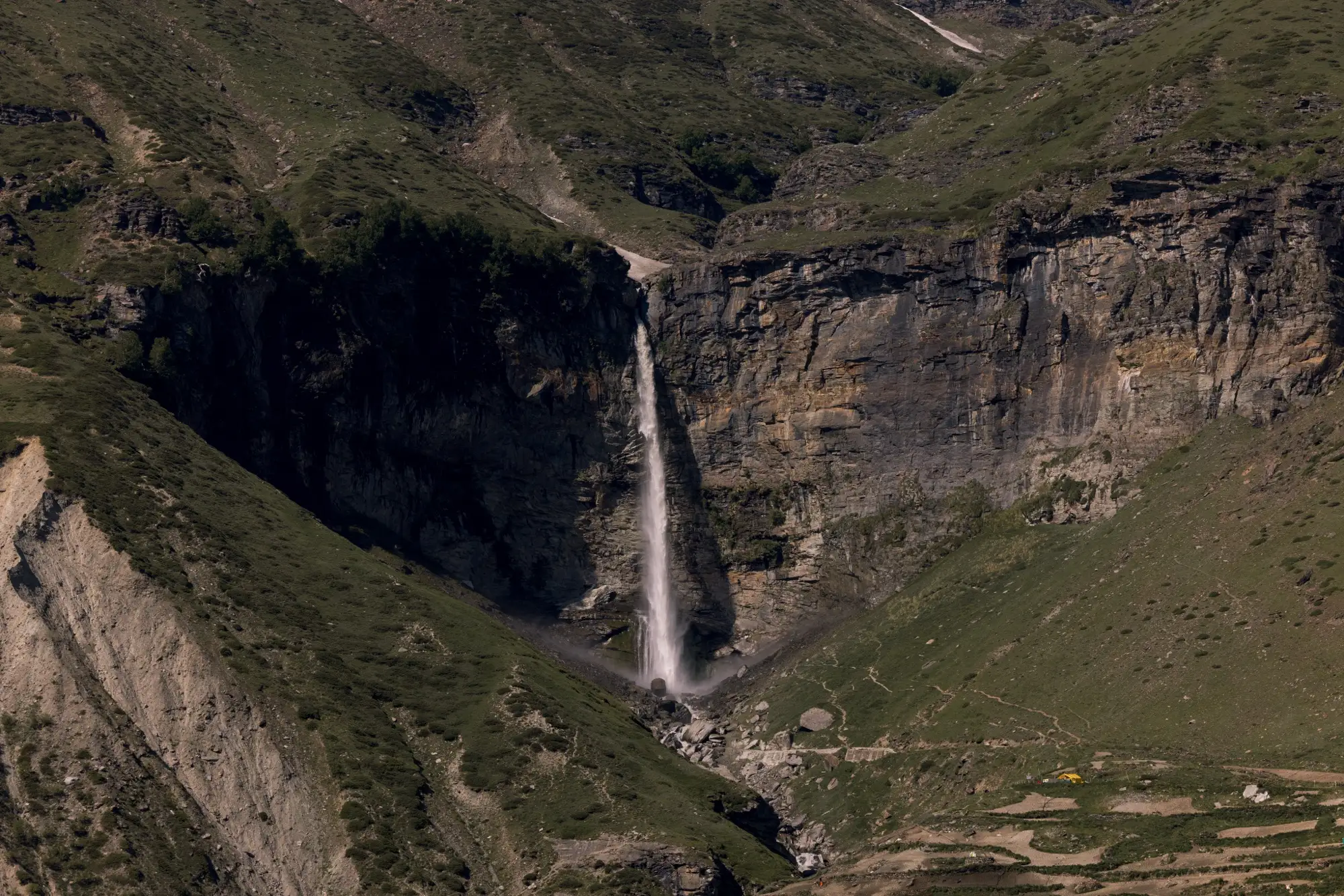 A tall waterfall dropping down a dark cliff at Sissu in the Lahaul valley