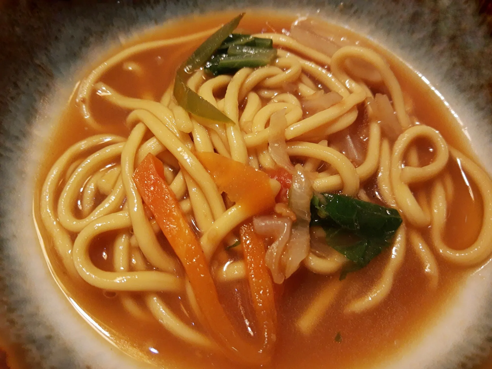 A bowl of thukpa, a Tibetan noodle soup with vegetables in a red broth