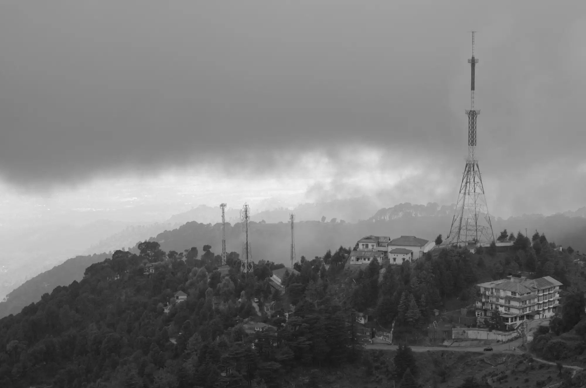 Cloud and rain over a ridge near upper Dharamshala in black and white, with mobile masts on the hilltop