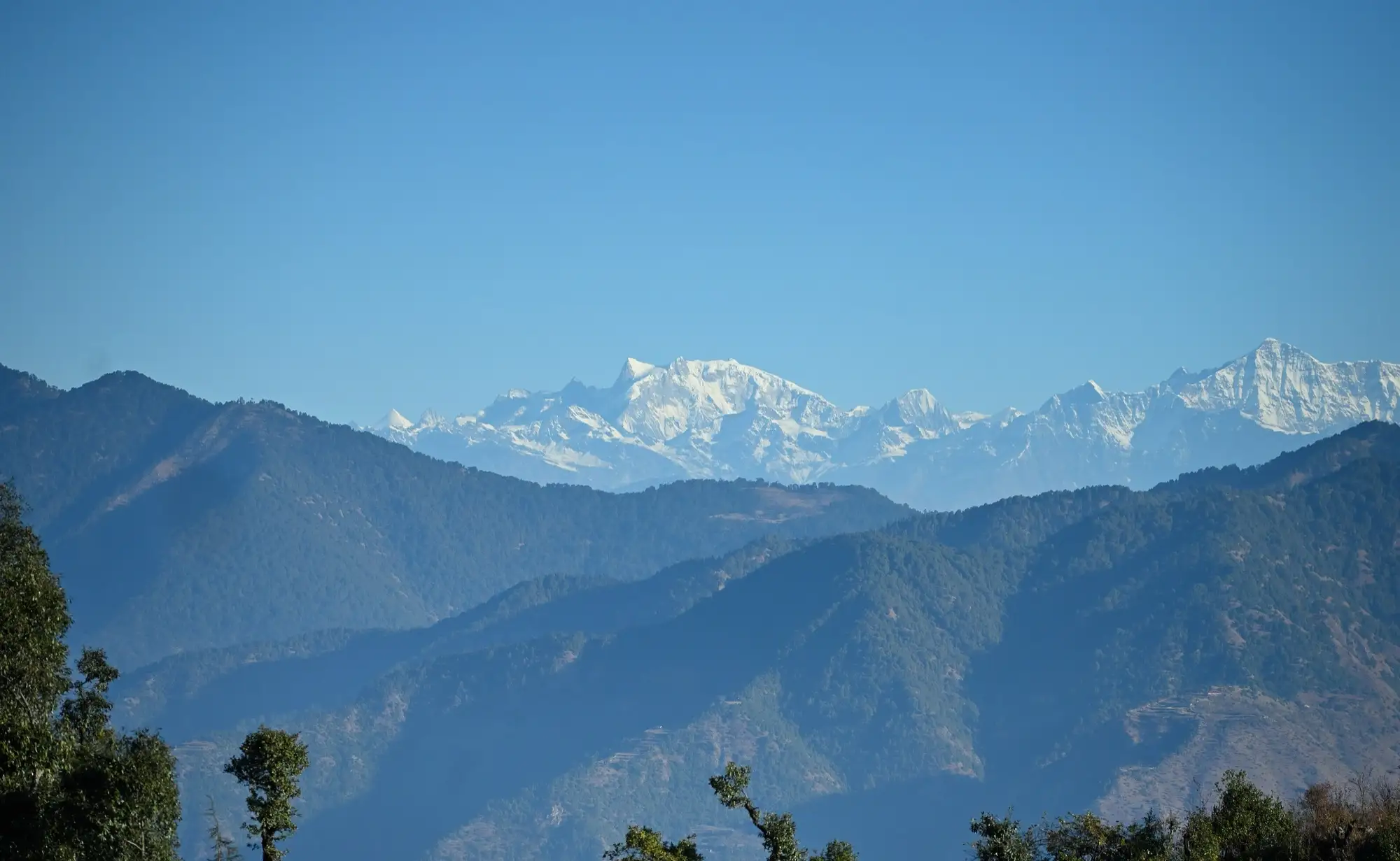 Snow peaks above forested ridges seen from Dhanaulti in January 2023